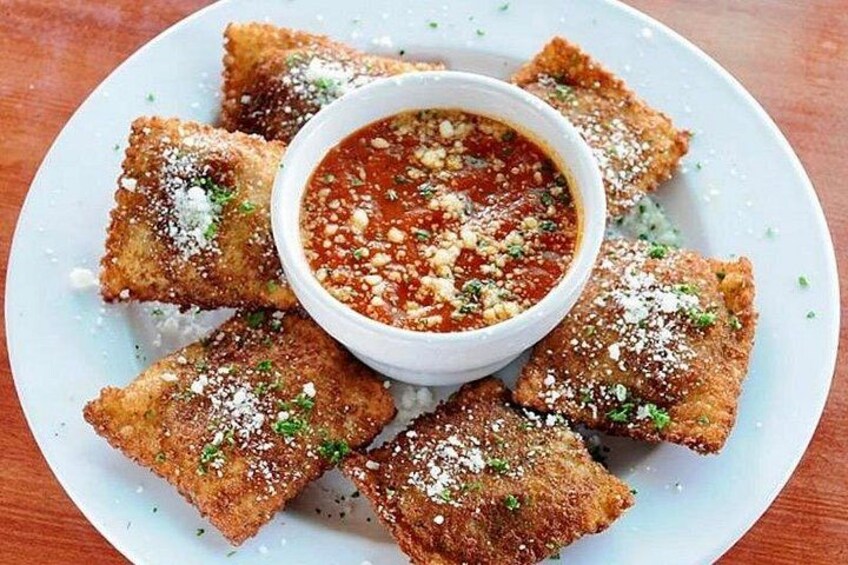 Un plato de comida rebozada y frita, posiblemente buñuelos, con un tazón de salsa roja en el centro. 2