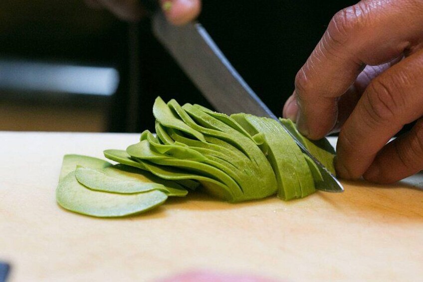 A person slicing a green vegetable on a cutting board. 2