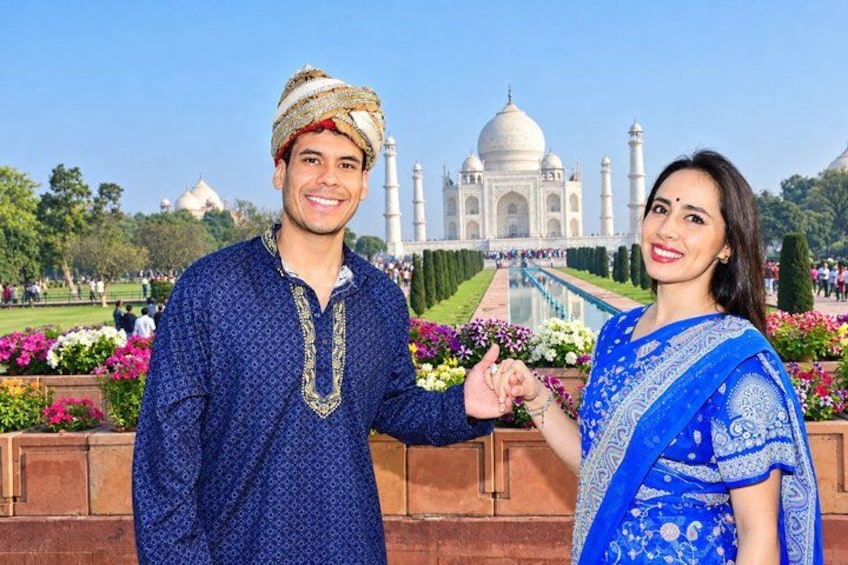 Ett par i traditionella kläder som står framför Taj Mahal. 4