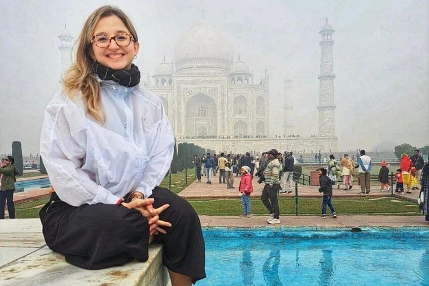 Une personne assise au bord d’une piscine, avec le Taj Mahal en arrière-plan. 2