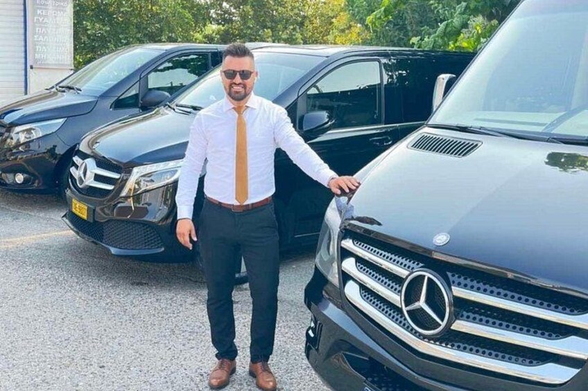A person standing next to a black Mercedes-Benz SUV in a parking lot. 1