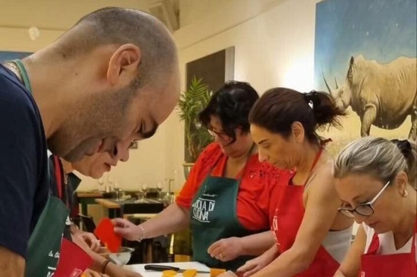 A group of people wearing aprons, engaged in a food preparation activity. 1