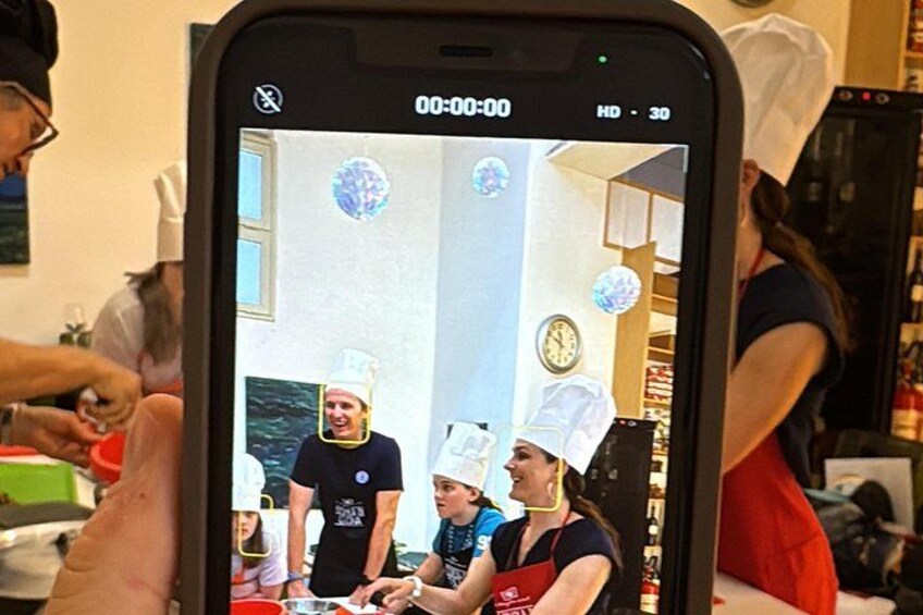 A smartphone displaying a video of people in a kitchen, some wearing chef hats. 4