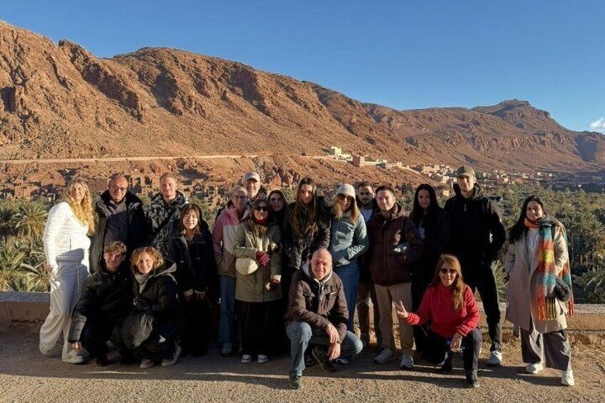 A group of people posing in front of a mountainous landscape with a town in the background. 5
