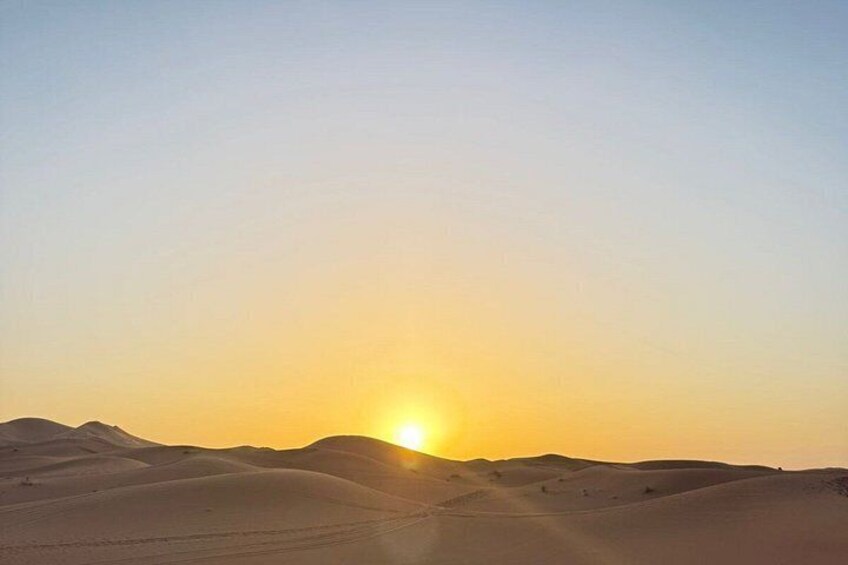 A desert landscape with sand dunes and a setting sun. 4