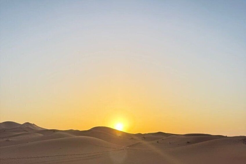 A desert landscape with sand dunes and a setting sun. 4