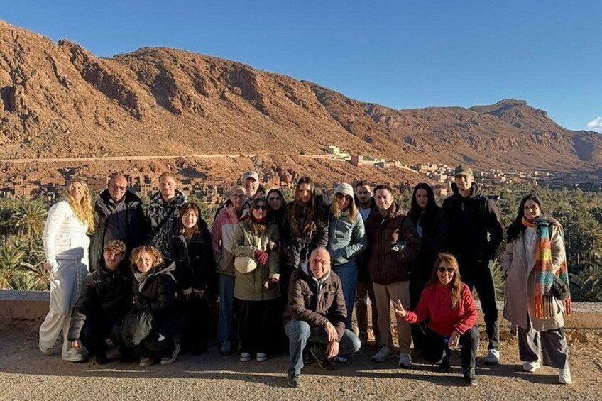 A group of people posing in front of a mountainous landscape with a clear sky. 5