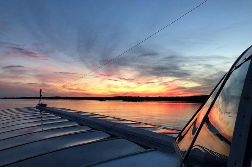 Een zonsondergang boven stil water, met een steiger en een boot. 3
