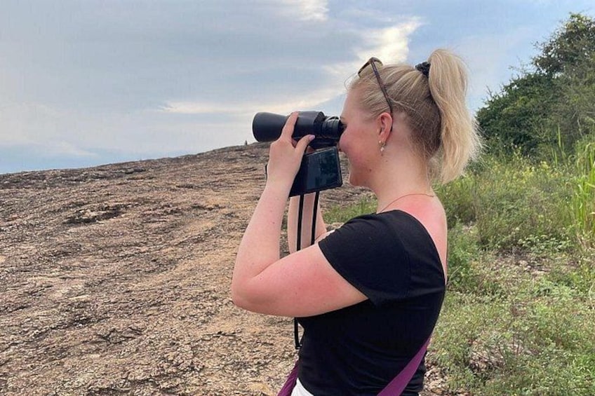 A person using a camera on a rocky terrain. 2