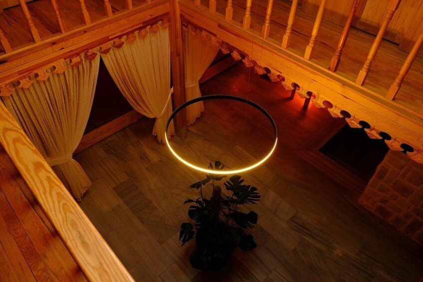 A wooden interior with a circular light fixture and curtains. 2