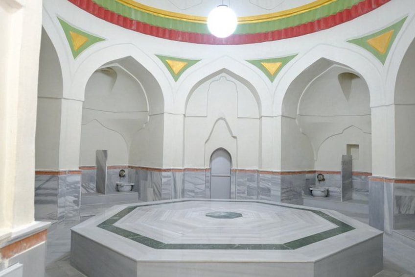 A large hall with a central circular platform, arched ceilings, and a patterned floor. 1