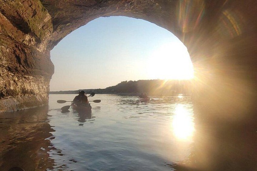 En person kajakroer under en naturlig klippeport med sollys der strømmer igennem. 3