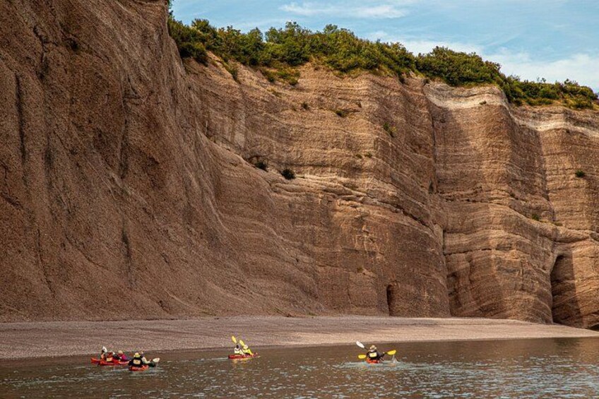 Kayakers on a calm river with steep cliffs in the background. 2