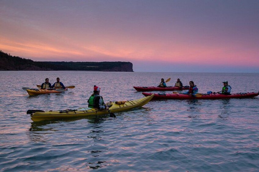 A group of people kayaking on a calm body of water during sunset. 3