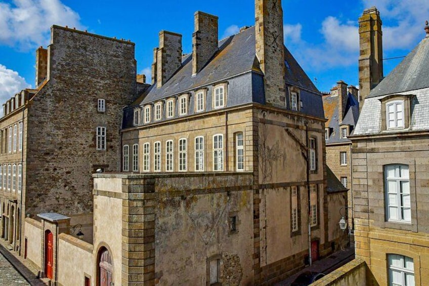 A historic stone building with multiple chimneys and arched windows. 2