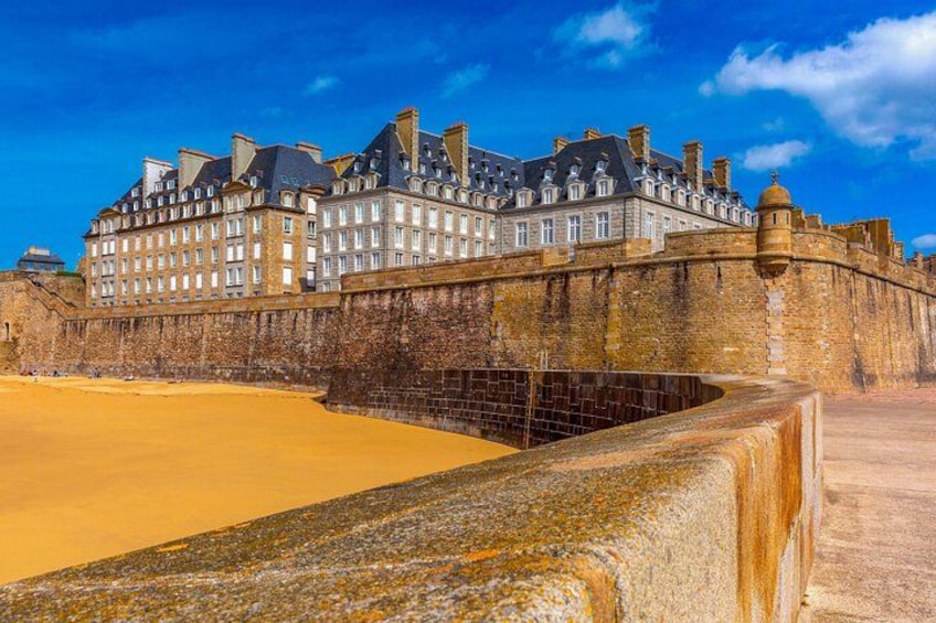 A historic building with a large courtyard and a sandy area in front. 4