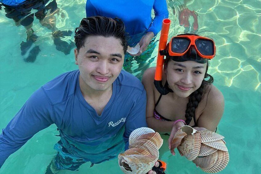 Zwei Personen beim Schnorcheln in klarem Wasser, sie halten Meeresschnecken. 4
