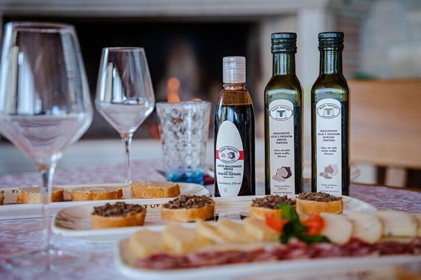 A table with various food items, wine glasses, and bottles of olive oil. 2