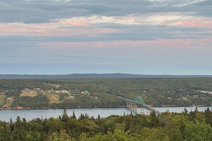 A bridge over a lake with surrounding forest and distant hills. 4