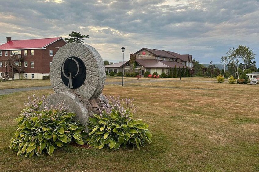 A large stone sculpture in a grassy field with a building in the background. 5