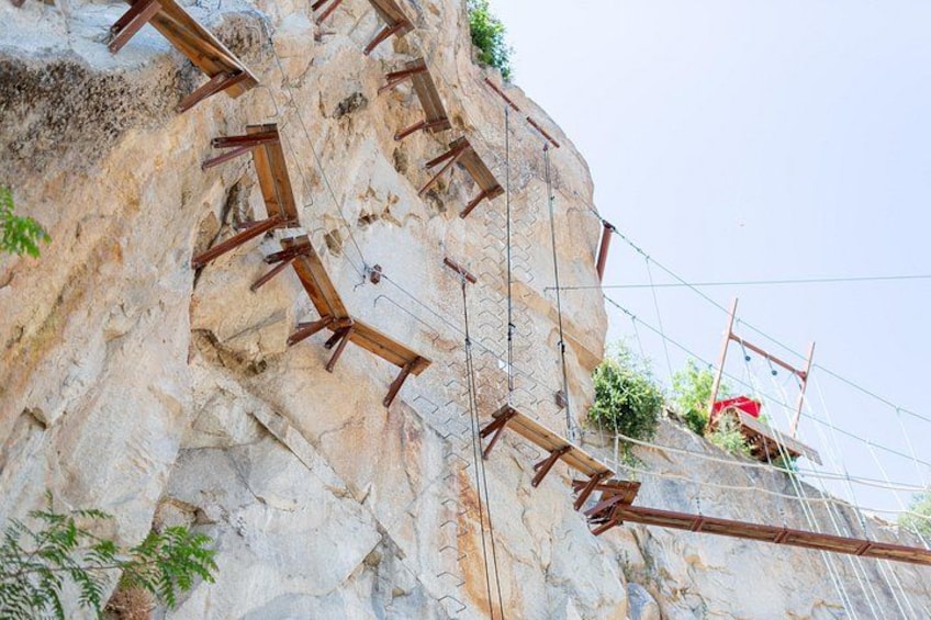 A rock climbing wall with wooden handholds and ropes. 3