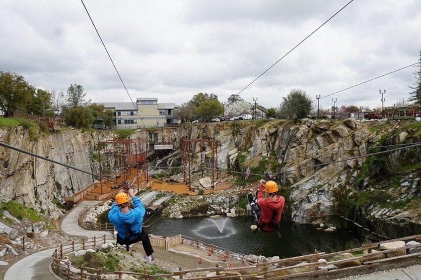 Two people rappelling down a rocky cliff with safety harnesses and helmets. 2