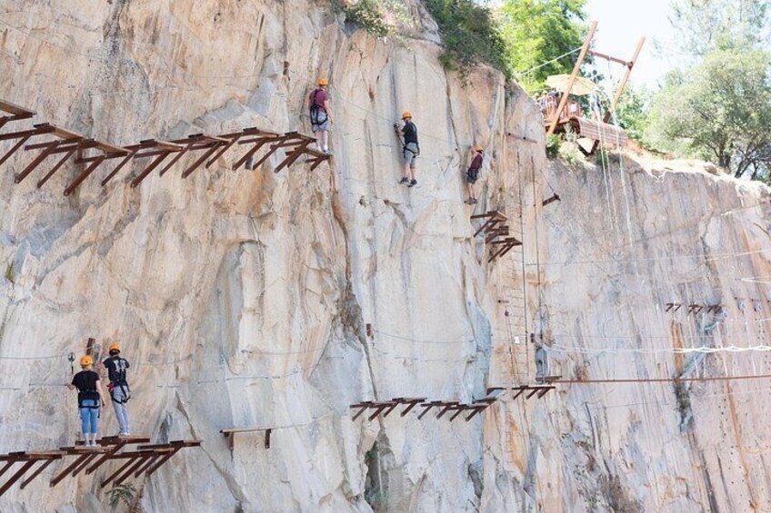 A rock climbing activity with wooden ladders and ropes on a large rock face. 3