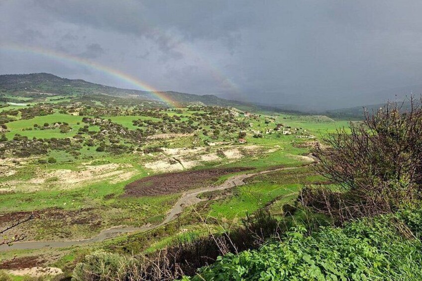 A rural landscape with a winding road, green fields, and a rainbow in the sky. 3