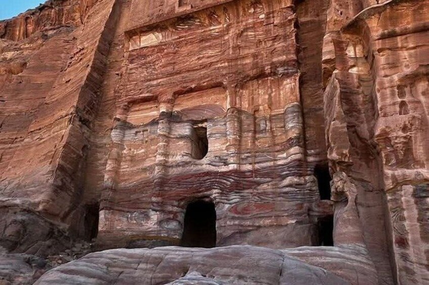 A rock formation with layered strata and multiple cave openings. 4