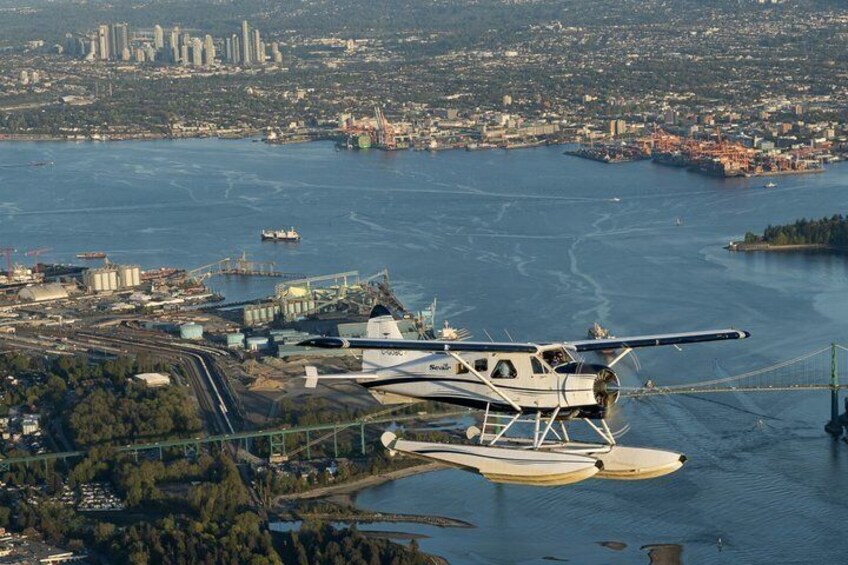 A seaplane over a body of water with a cityscape in the background. 2