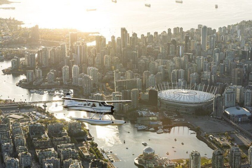 A cityscape with a stadium, high-rise buildings, and a river with boats. 1