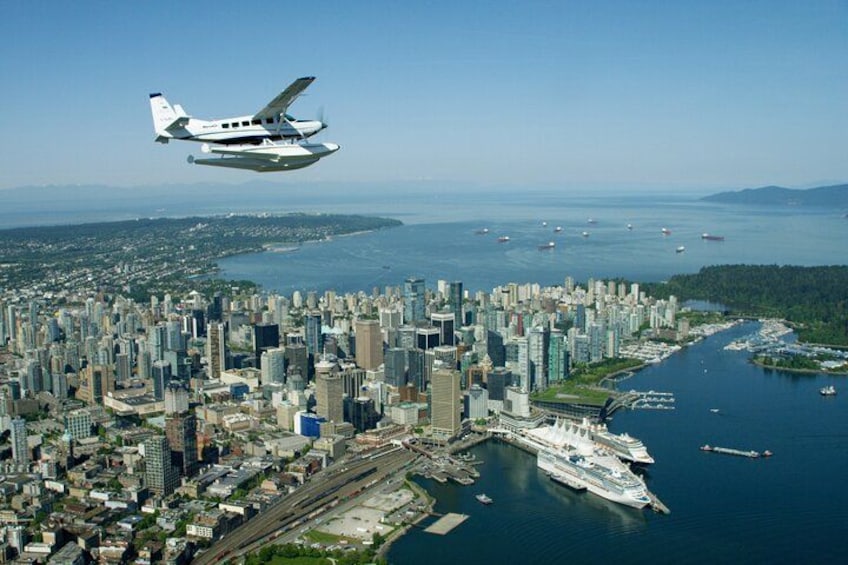 A cityscape with a large body of water, a ferry terminal, and a seaplane in the sky. 2