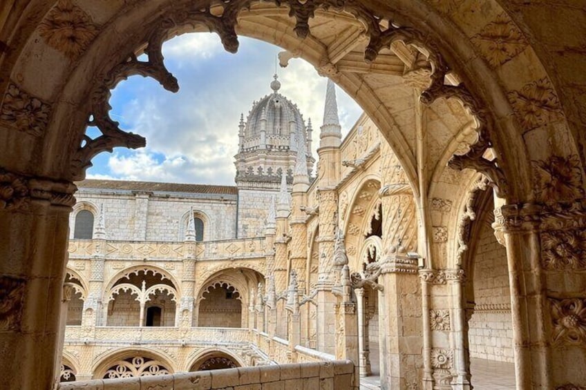 An ornate stone archway framing a historic building with intricate carvings and a prominent tower. 4
