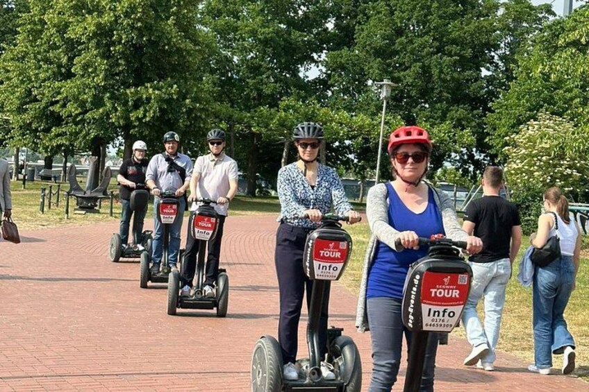People riding Segways on a paved path in a park. 2