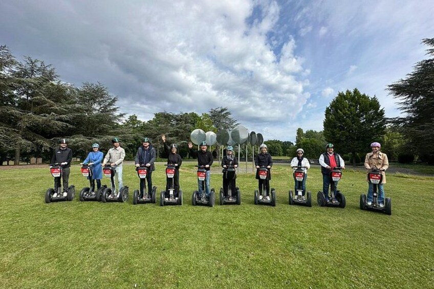 A group of people on segways in a grassy field with trees in the background. 4