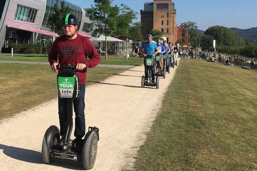 A person on a Segway, a group of people on bicycles, and a castle-like building in the background. 1