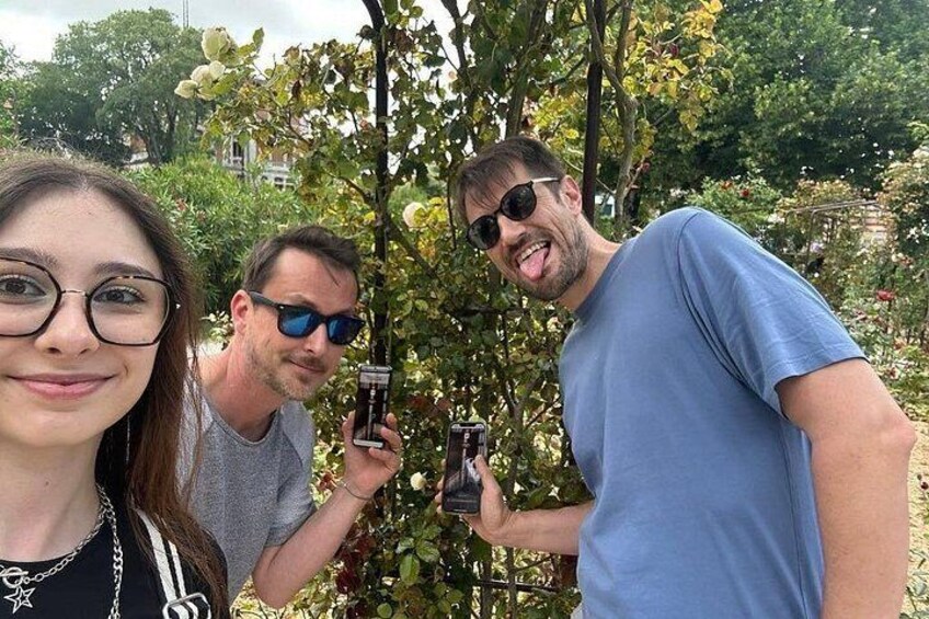 Three people outdoors, holding bottles, with trees and a fence in the background. 4