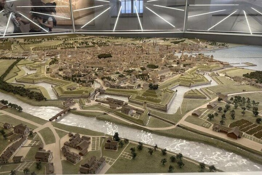Une maquette détaillée d’une ville avec une rivière, des fortifications et un pont. 3
