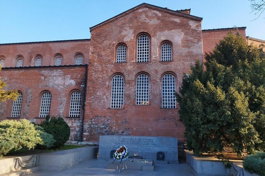 A red brick building with arched windows and a plaque in front. 4