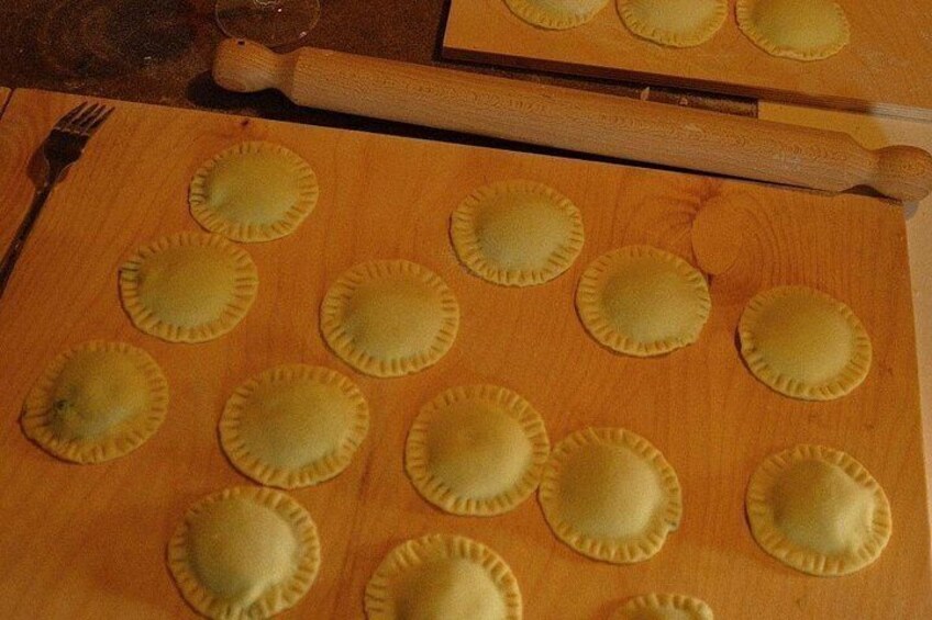 A wooden cutting board with several round, yellow pastry dough pieces arranged on it. 5
