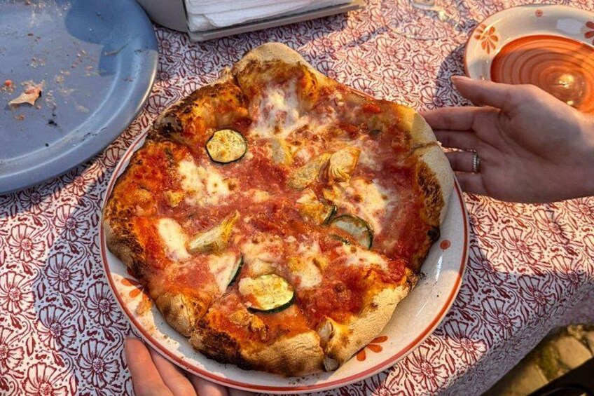 A pizza with zucchini on a patterned tablecloth. 3