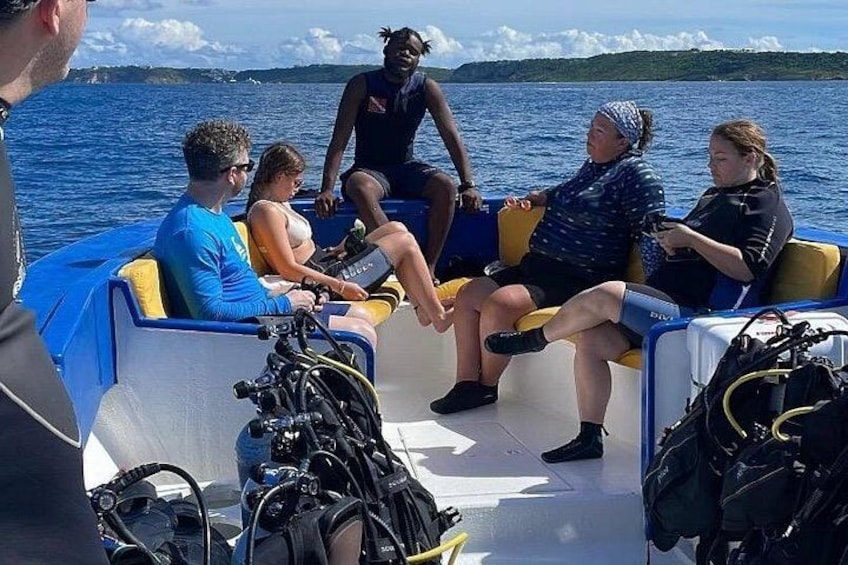 A group of people on a boat with scuba diving equipment visible. 1