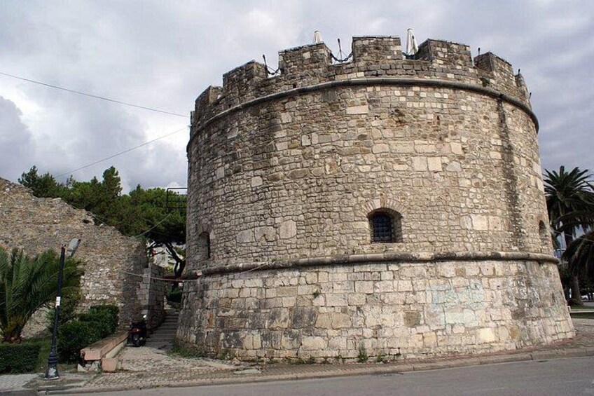 A historic stone tower with battlements, a narrow entrance, and a paved pathway leading up to it. 2