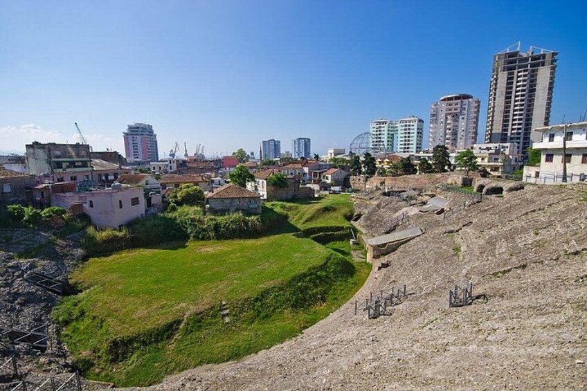 A cityscape with a mix of residential buildings and high-rise structures, a grassy area, and a hilly terrain. 3