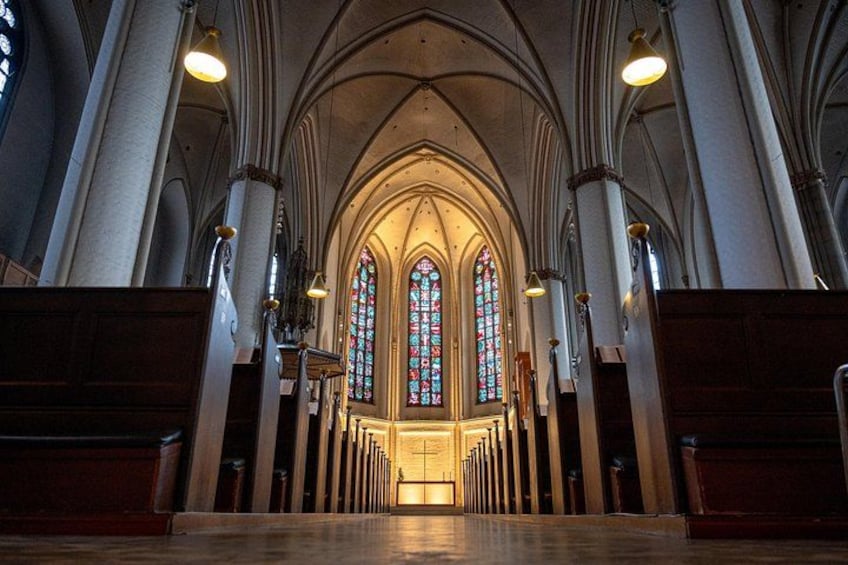 A cathedral interior with arched ceilings, stained glass windows, and rows of pews. 2