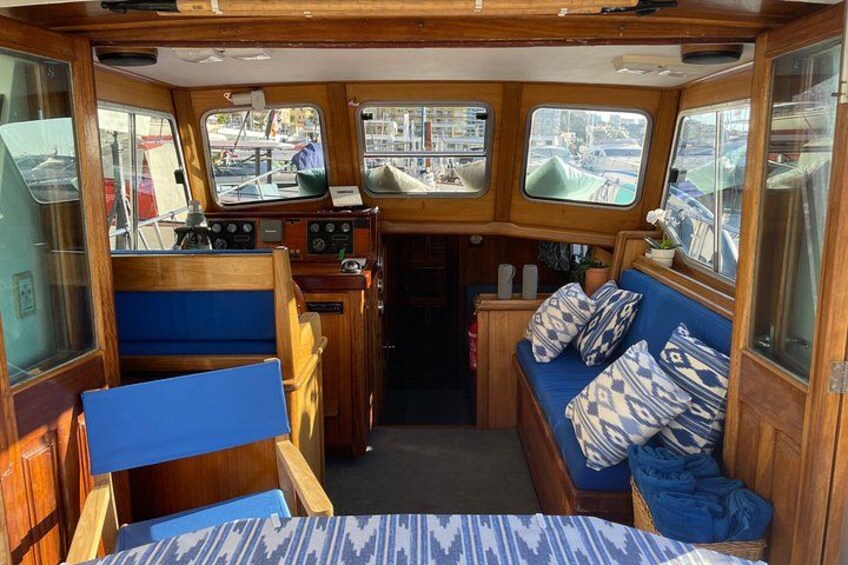 L'intérieur d'un bateau, avec une cabine en bois, des sièges bleus et des fenêtres. 2