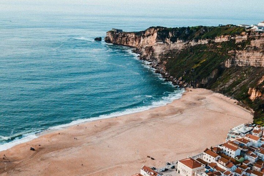 Un pueblo costero con playa, acantilados y edificios. 2