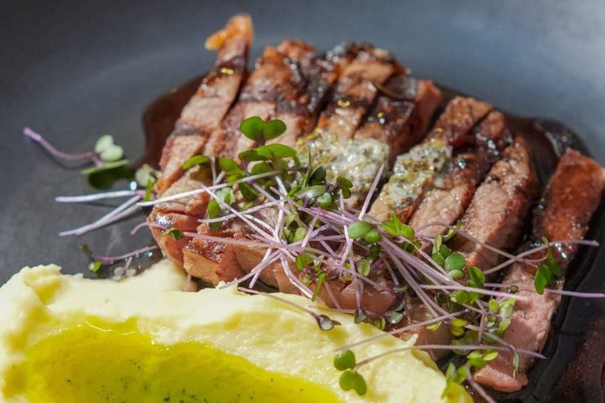 A plate of sliced meat with sprouts and a yellow sauce. 2