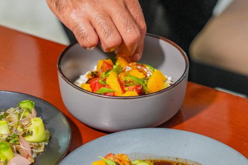A person serving a dish with diced mango and vegetables in a bowl. 3