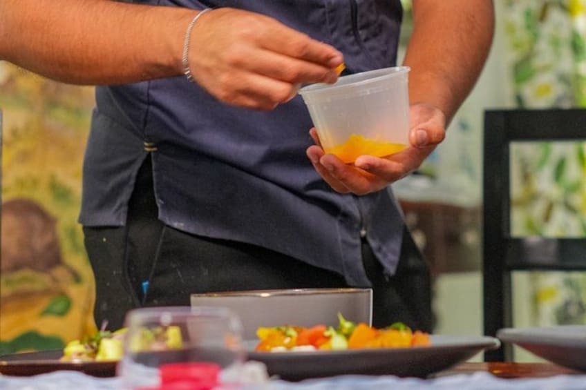 A person holding a plastic cup with a yellow liquid, possibly juice or a drink, and a plate with food in the foreground. 4